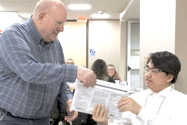 A student handing his taxes homework to his professor