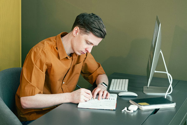 Student taking notes at desktop computer