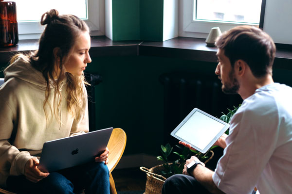 Two students using laptop and tablet