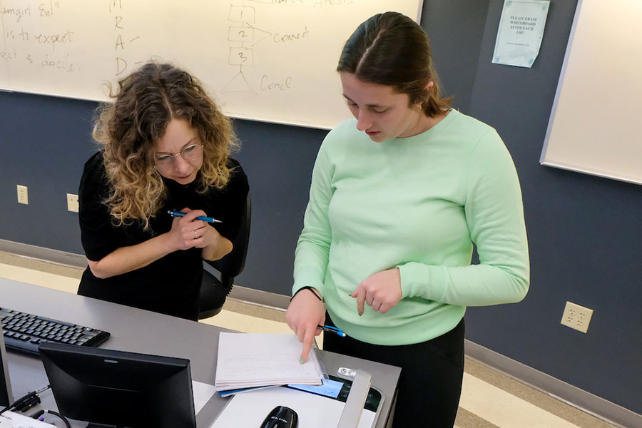 Teacher and student reviewing work in a notebook