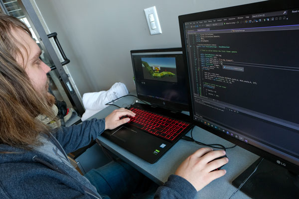 Student coding on two computers