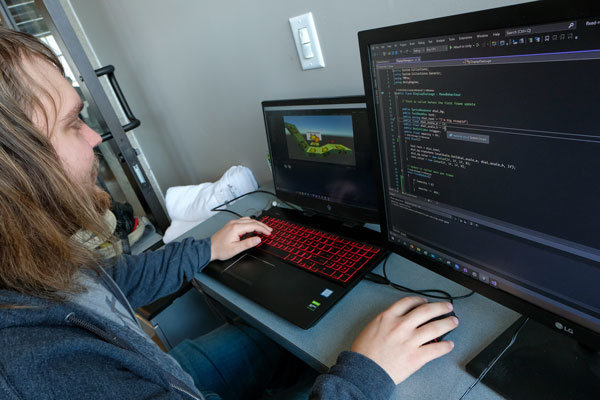 Student coding on two computers