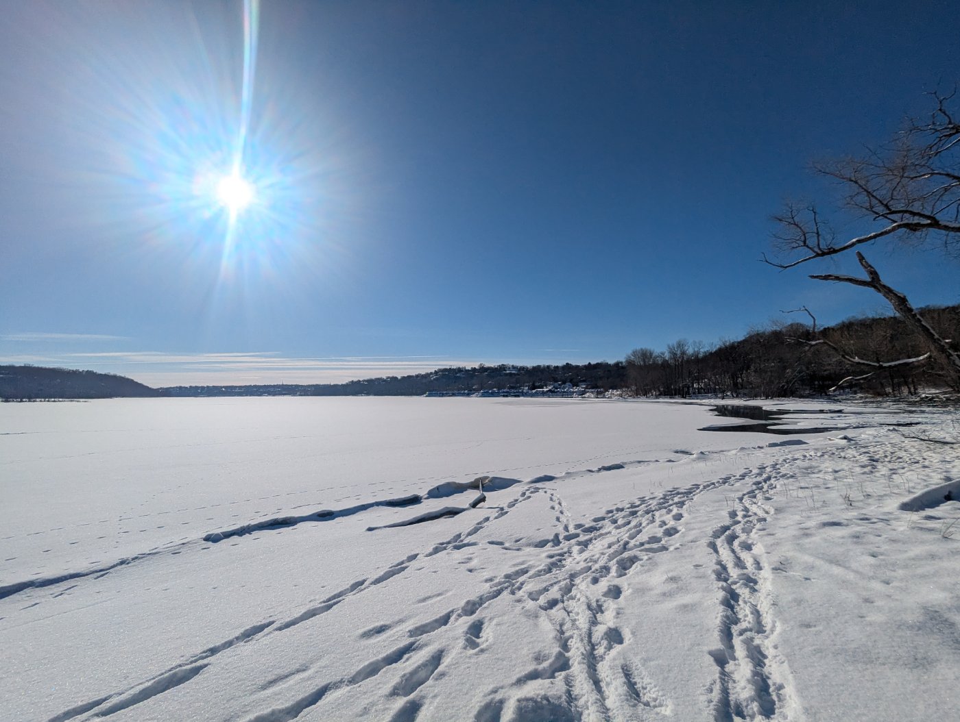 Photo of footprints in the snow under a bright blue winter sky.