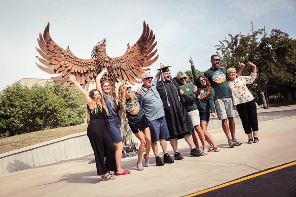 Group of students pose in front of UW-Green Bay Phoenix sculpture