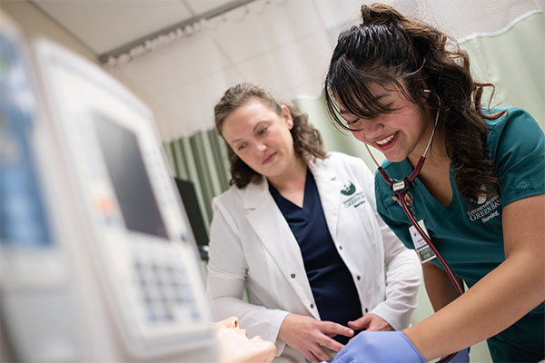 A Nursing student practices a clinical procedure on a training mannequin in a simulation lab.