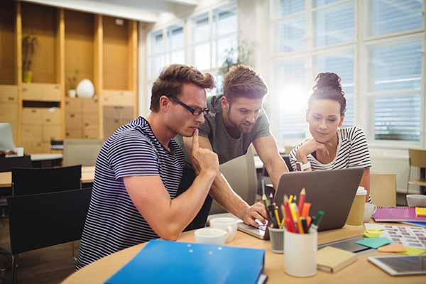 three people sitting at computer discussing event needs