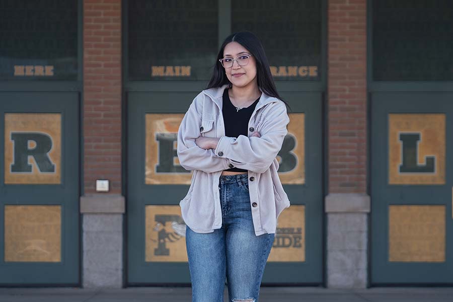 Vanessa, Rising Phoenix student, standing in front of high school entrance