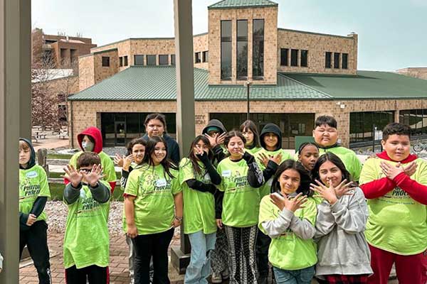 5th graders making Wings hand gesture in front of the UWGB Union