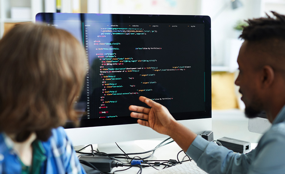 man gesturing towards computer monitor