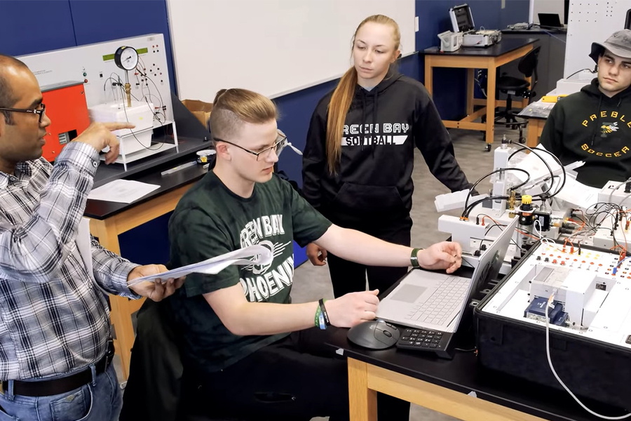 Engineering students at a table with several pieces of equipment.