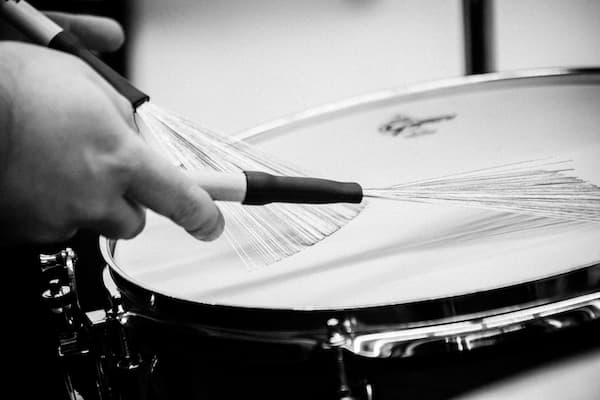 Black and white photo of drum brushes plaing a snare drum, percussion
