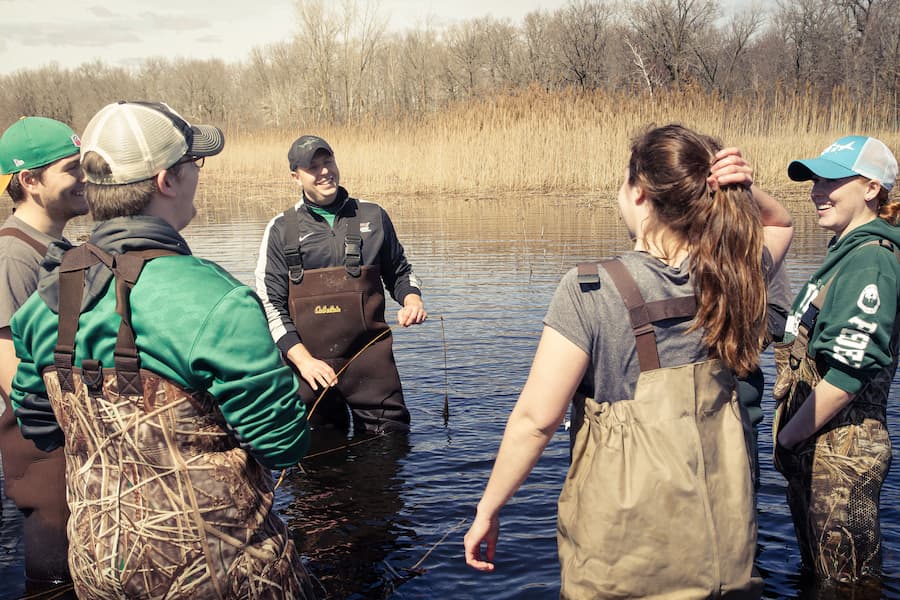 Patrick Forsythe's water science class in bib waders standing in a body of water