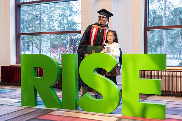 UWGB grad and child pose with RISE letter photo opp
