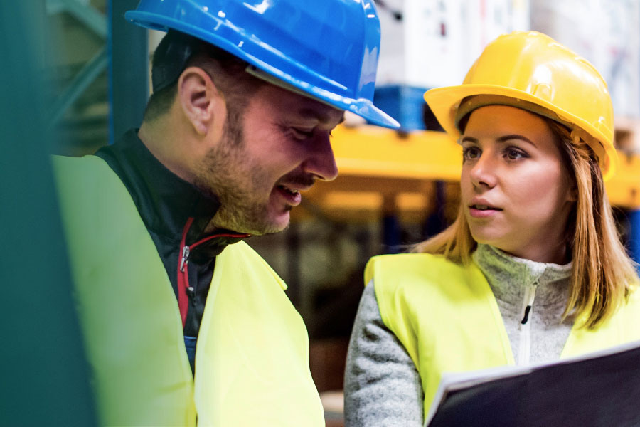 Male and female supply chain employees in hard hats