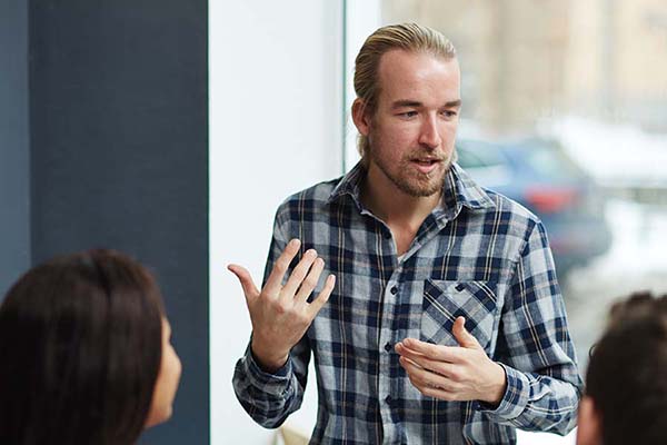 man instructor wearing plaid shirt talking to class participants