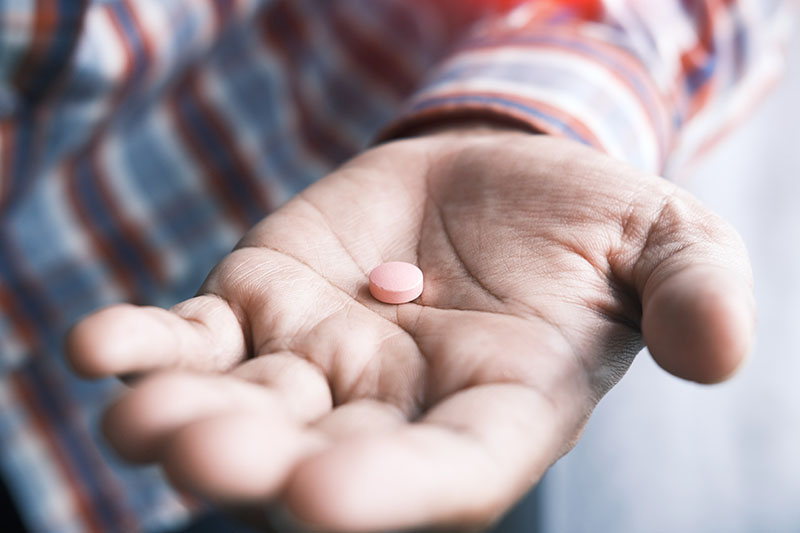 Elderly person with pill in their hand