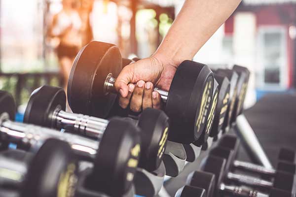 Hand reaching lifting a dumbbell from a rack