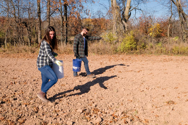 People spreading seed from buckets