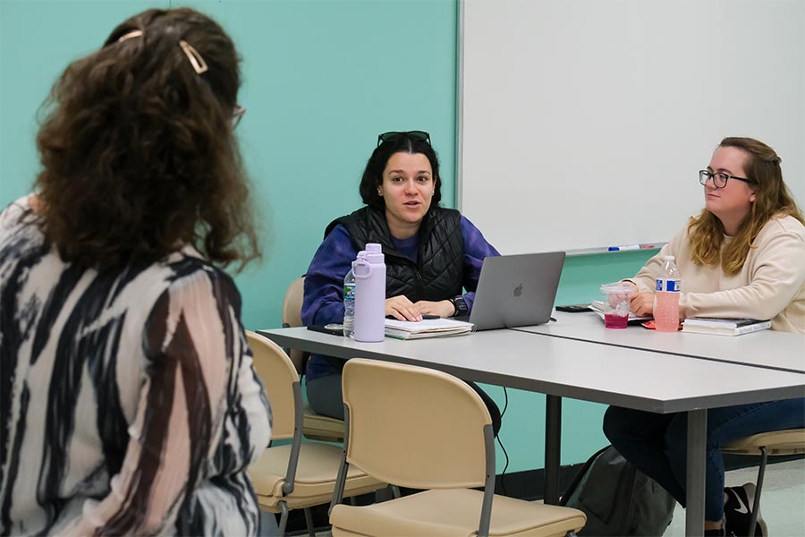Graduate students collaborate in a graduate class, using notebooks and a laptop.