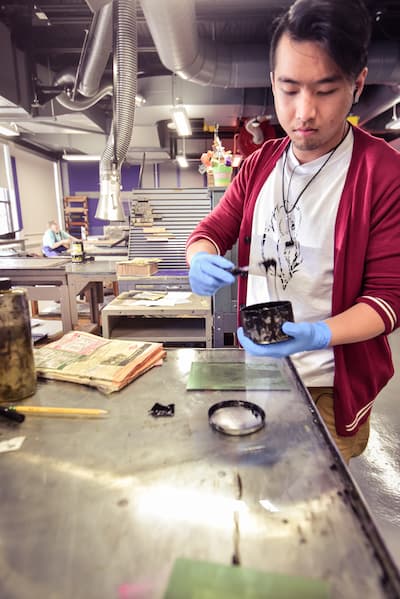 Male Asian students works on a project in the print studio