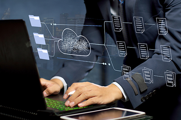 Conceptual photo of man working on laptop with cloud based files overlayed