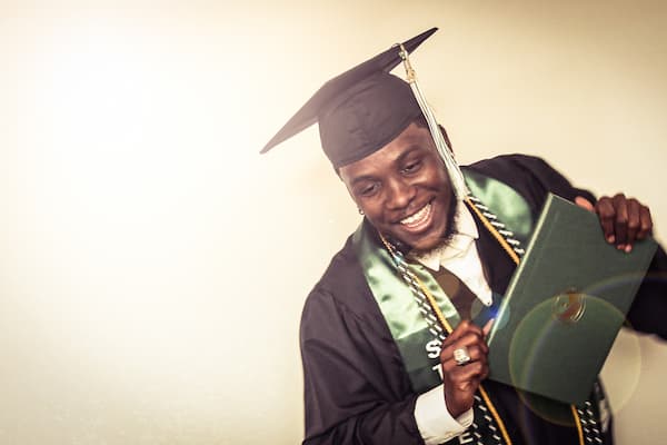 Black male graduate holding diploma.