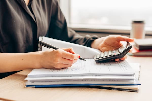 Student works on finances at desk with notebook, pen and calculator