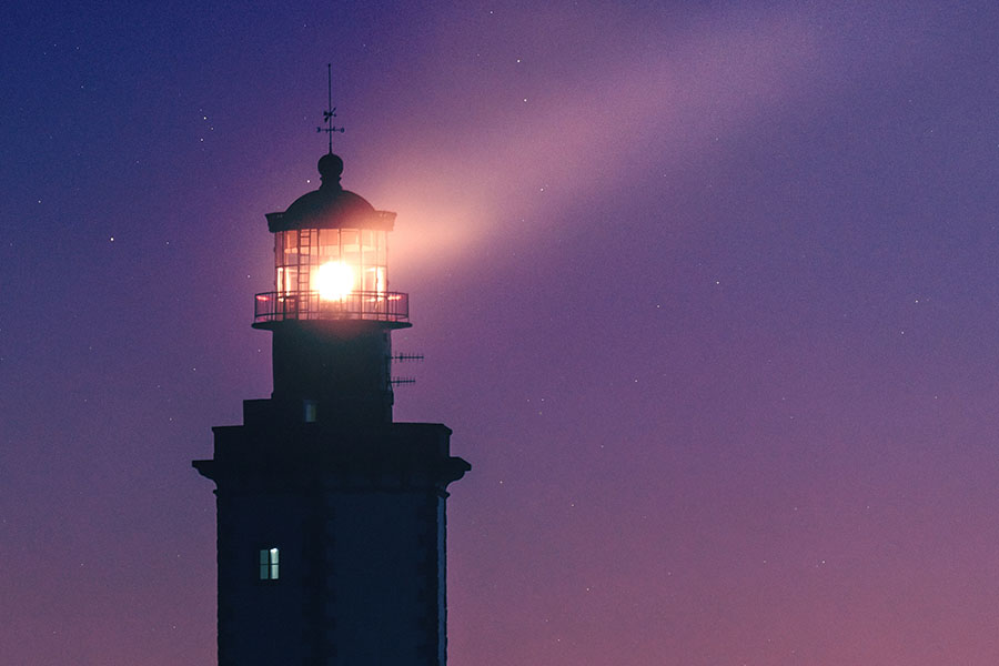 lighthouse against starry night purple sky