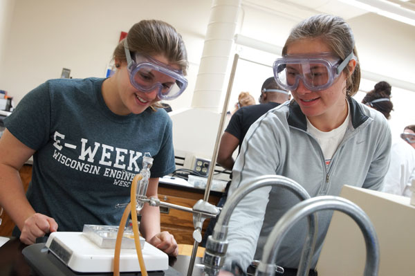 Two female students wearing safety goggles in chemistry lab