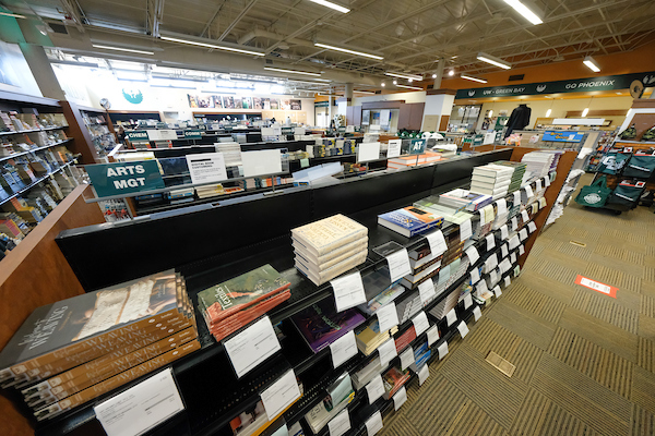 Stacks of textbooks sit on several rows of shelves with labels.