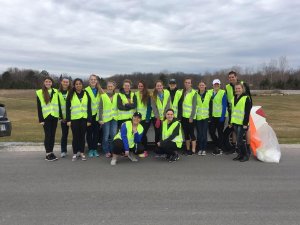 Students in reflective vests doing highway cleanup