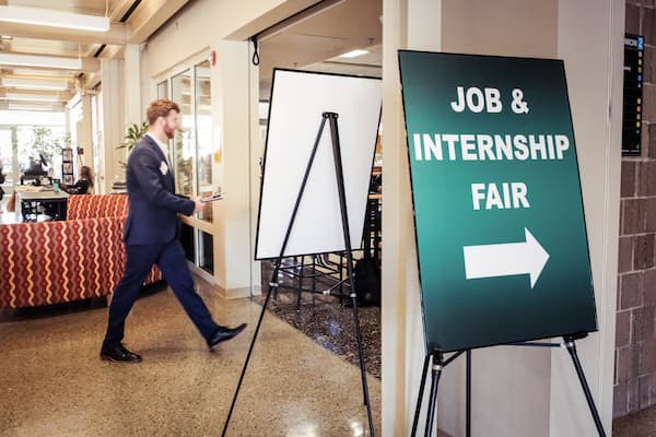 Male student wearing business suit walks into job and internship fair