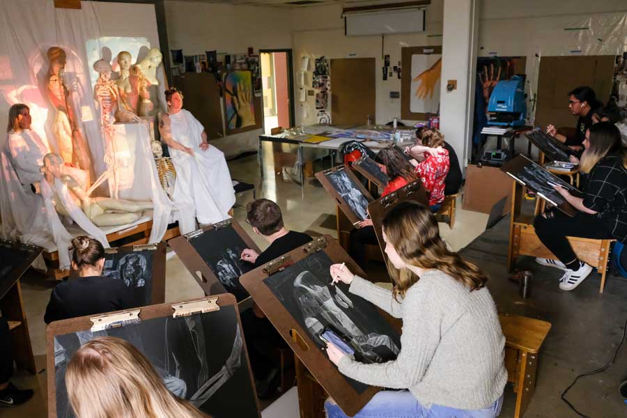 Students draw live models in figure drawing studio