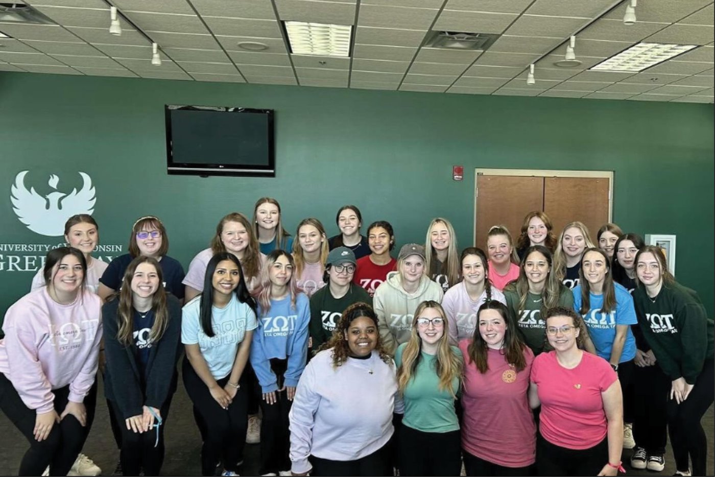 Zeta Omega Tau members pose for a group photo, all wearing ZOT shirts