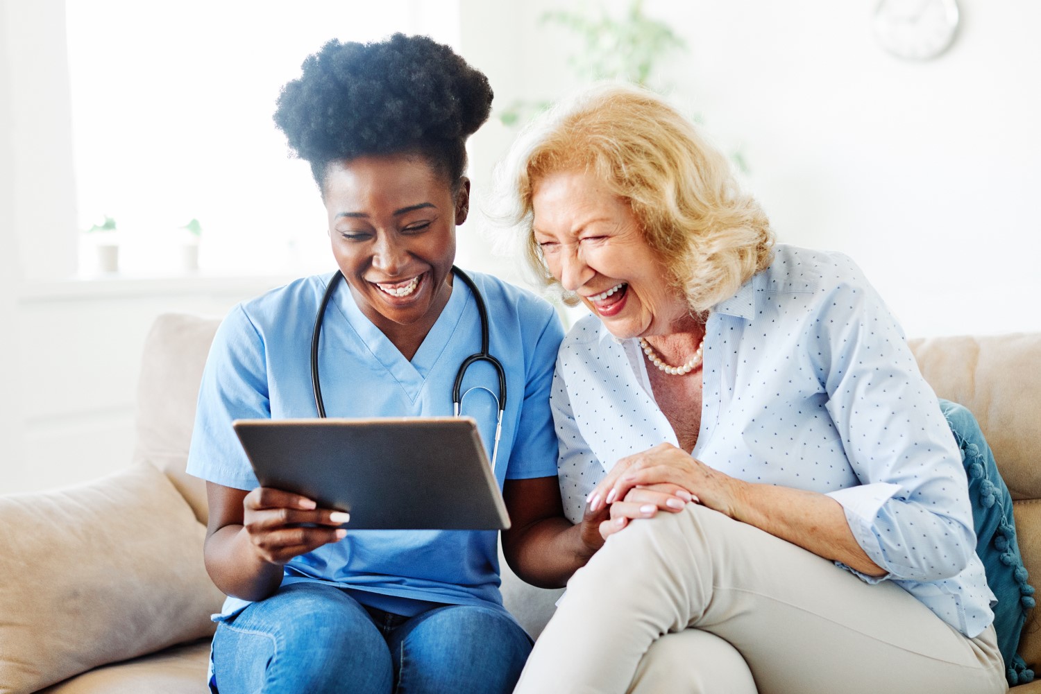 Caregiver looking at tablet with older woman