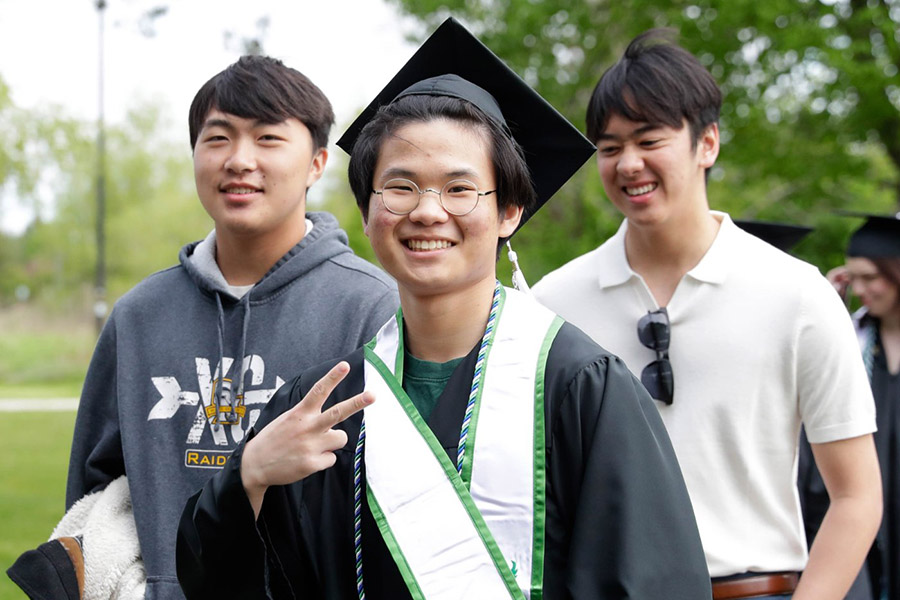 Student in grad cap and gown, walking with friends outdoors