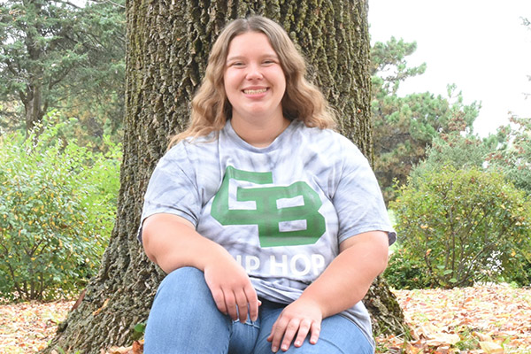 Annissa Derbique seated beside an oak tree