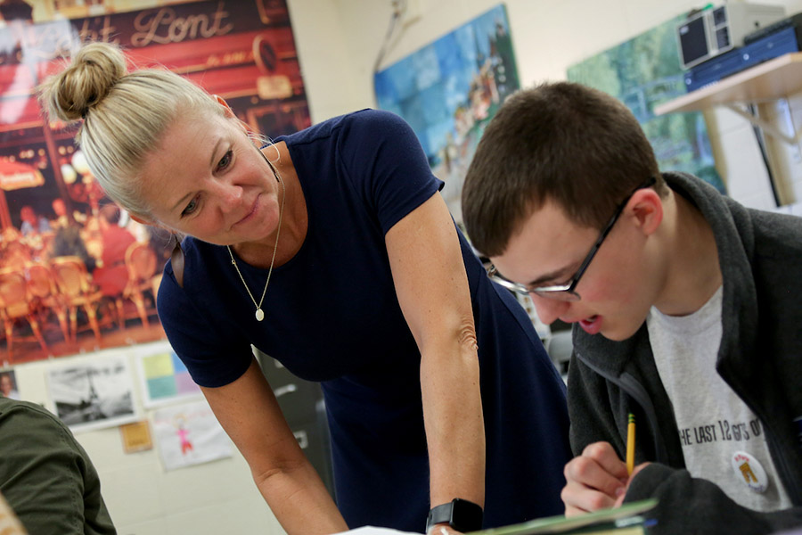 Teacher working with student at his desk