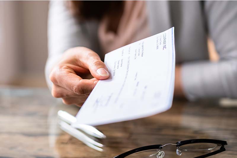 closeup of business womans hand holding out check