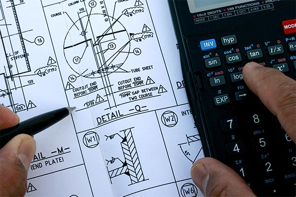 Mechanical engineer using a scientific calculator to check drawings