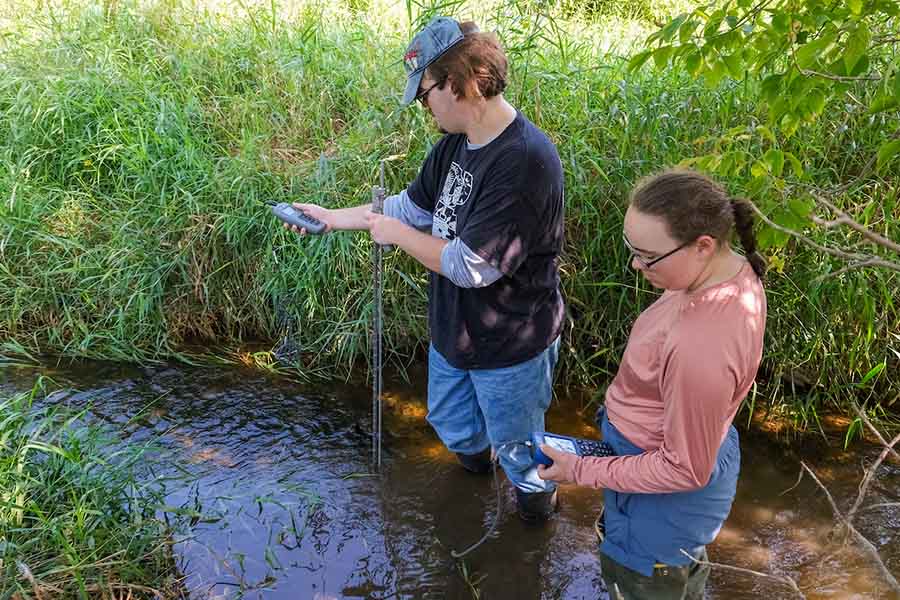 Students collecting water samples in a stream