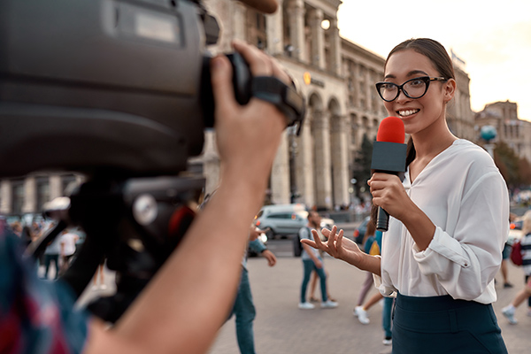 Reporter with cameraman outside of a pillared building