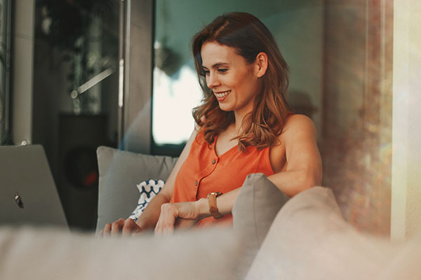 Woman sitting on couch looking at laptop