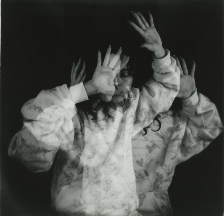 B&W double exposure photo of a woman with her hands up in a defense pose