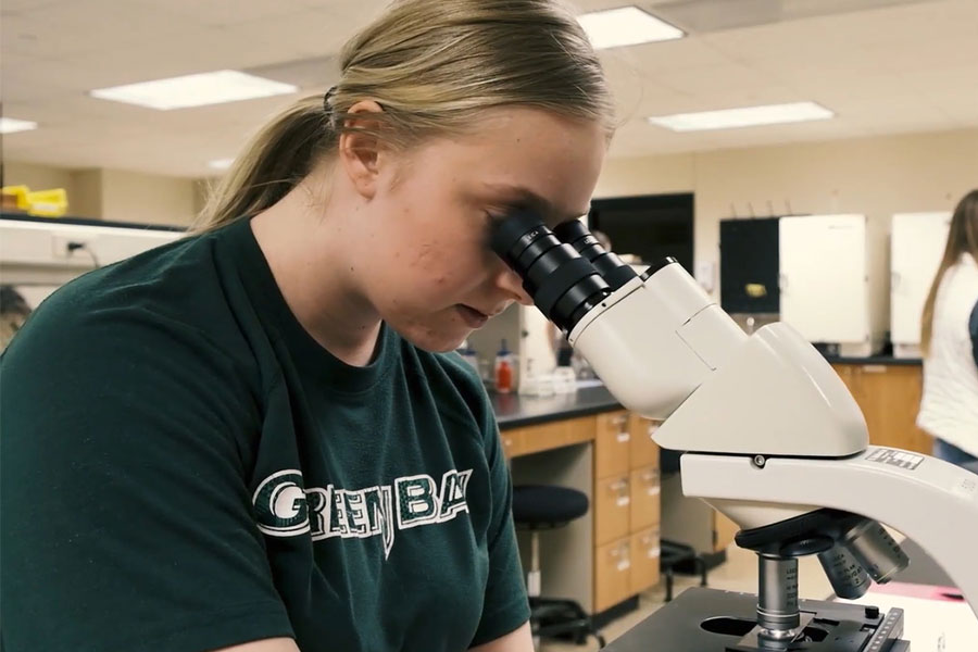 Female student looking in a microscope.