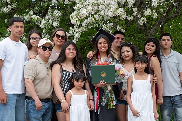 Una graduada de la UWGB, que lleva una estola mexicana, posa para una foto rodeado de su familia.