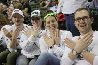 four people in UWGB regalia making a phoenix with their hands