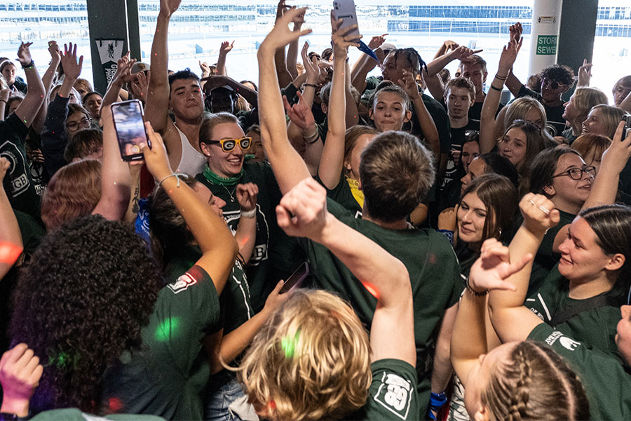 A large number of students celebrate at Lambeau Field with the football field in the background.