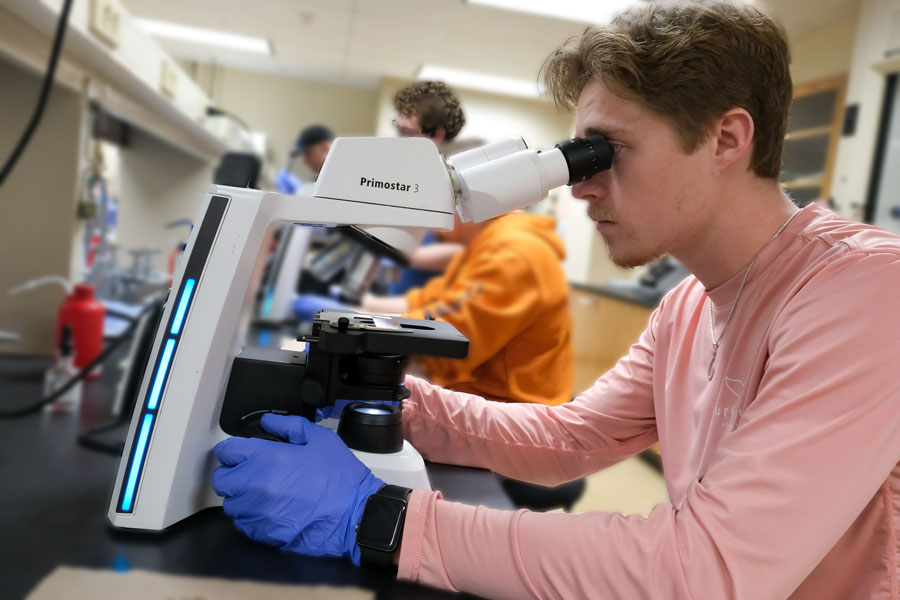 Male student looks into microscope