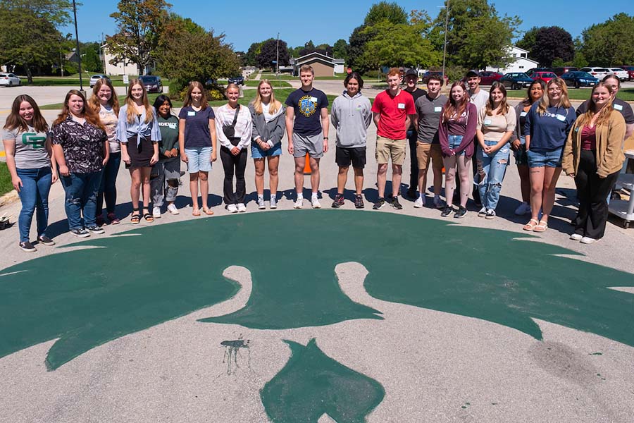 Students in front of a phoenix painting on ground